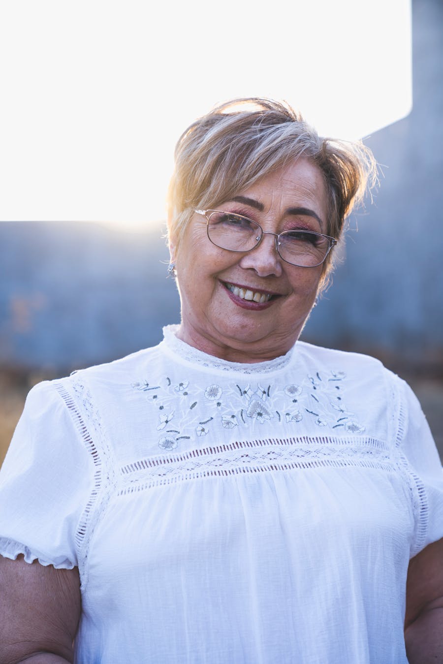 A woman in soft sunlight, wearing glasses