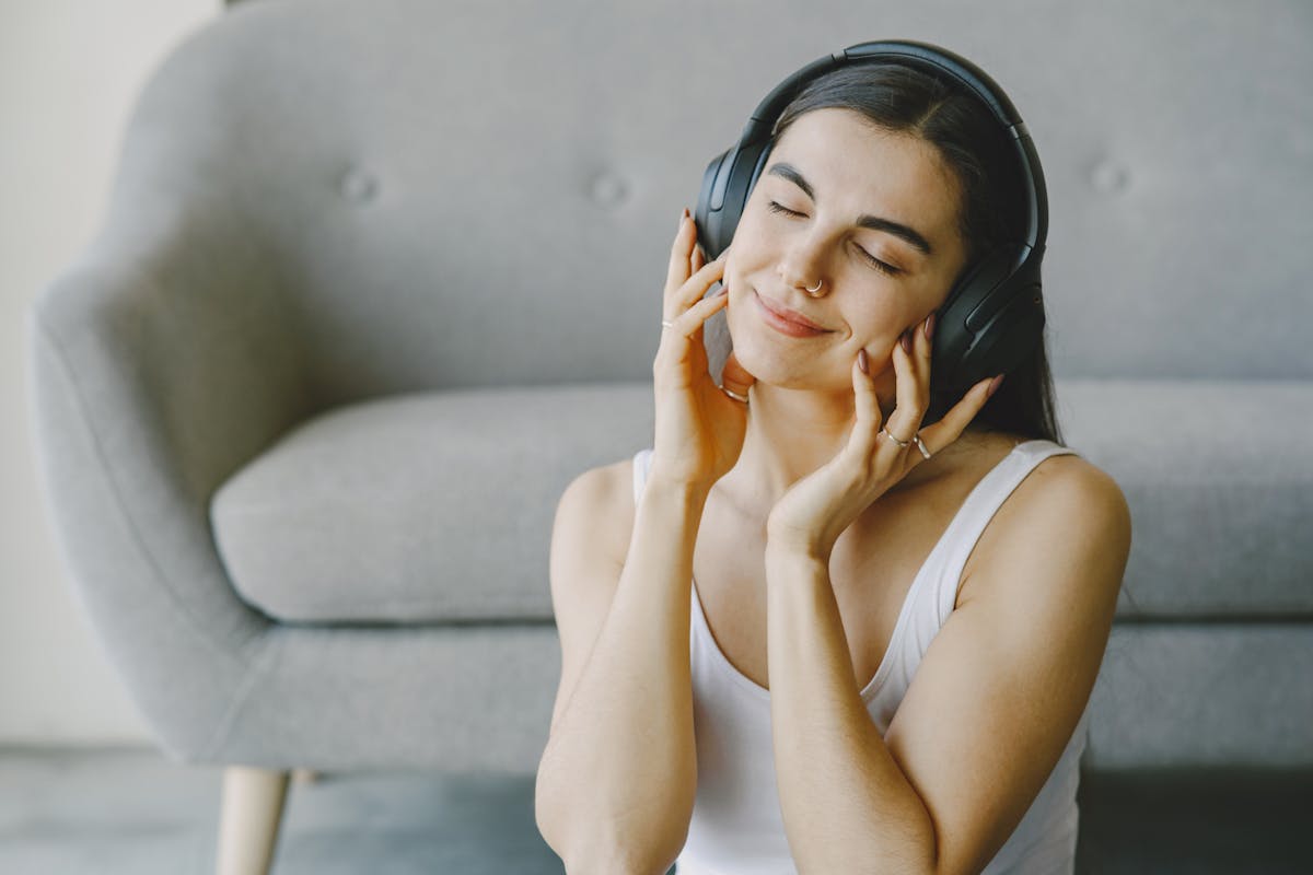 A woman wearing headphones with eyes closed, enjoying a calming sound session